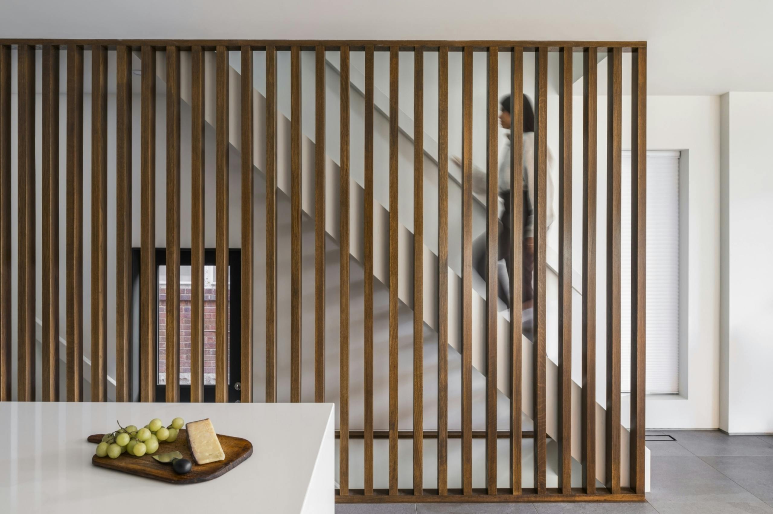 Wood slat wall screen acts as necessary guard for the stairs, but adds some design interest as a sculptural element